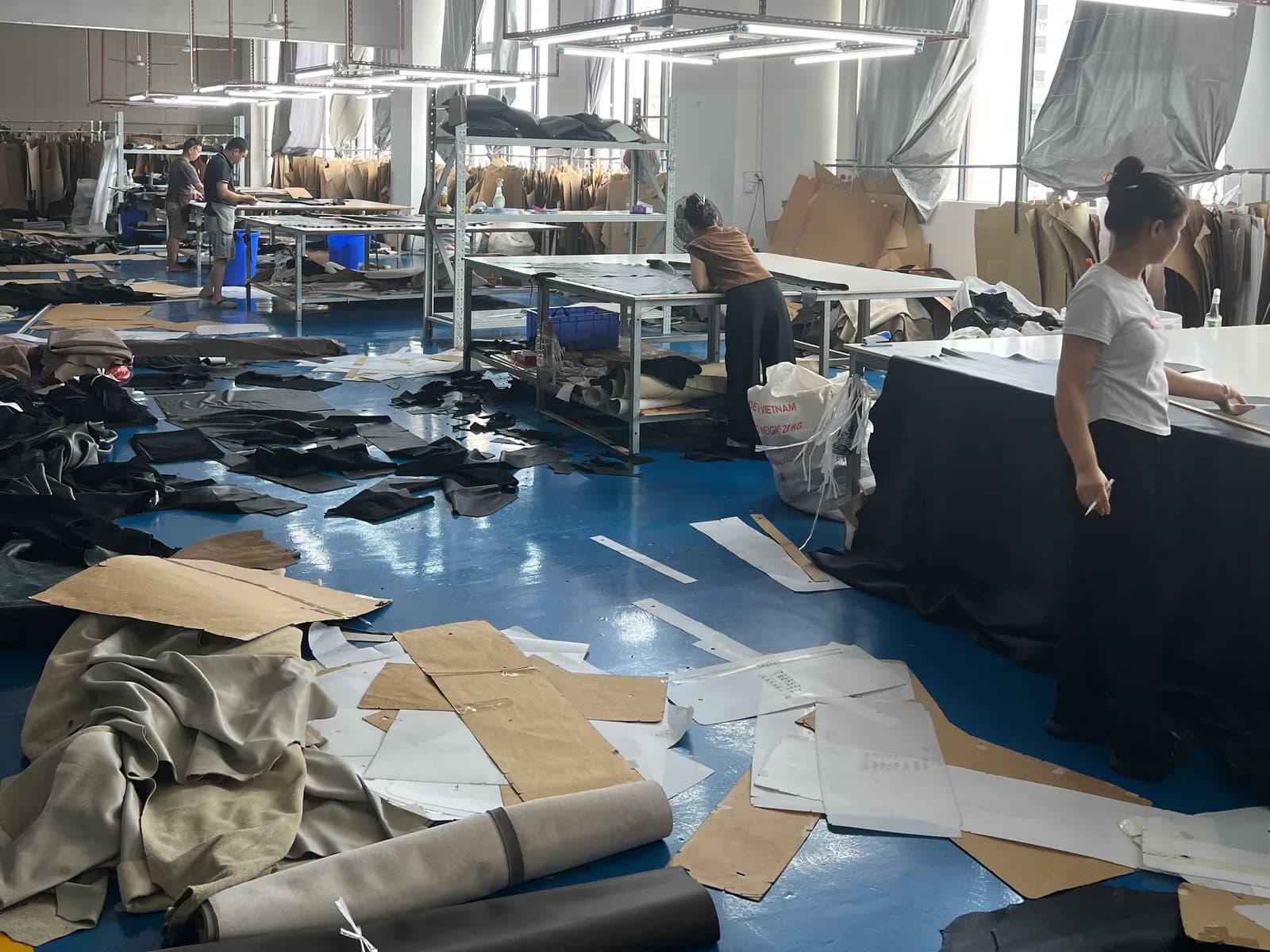 Pattern and cutting room with paper patterns on racks and team members marking out fabric on cutting tables