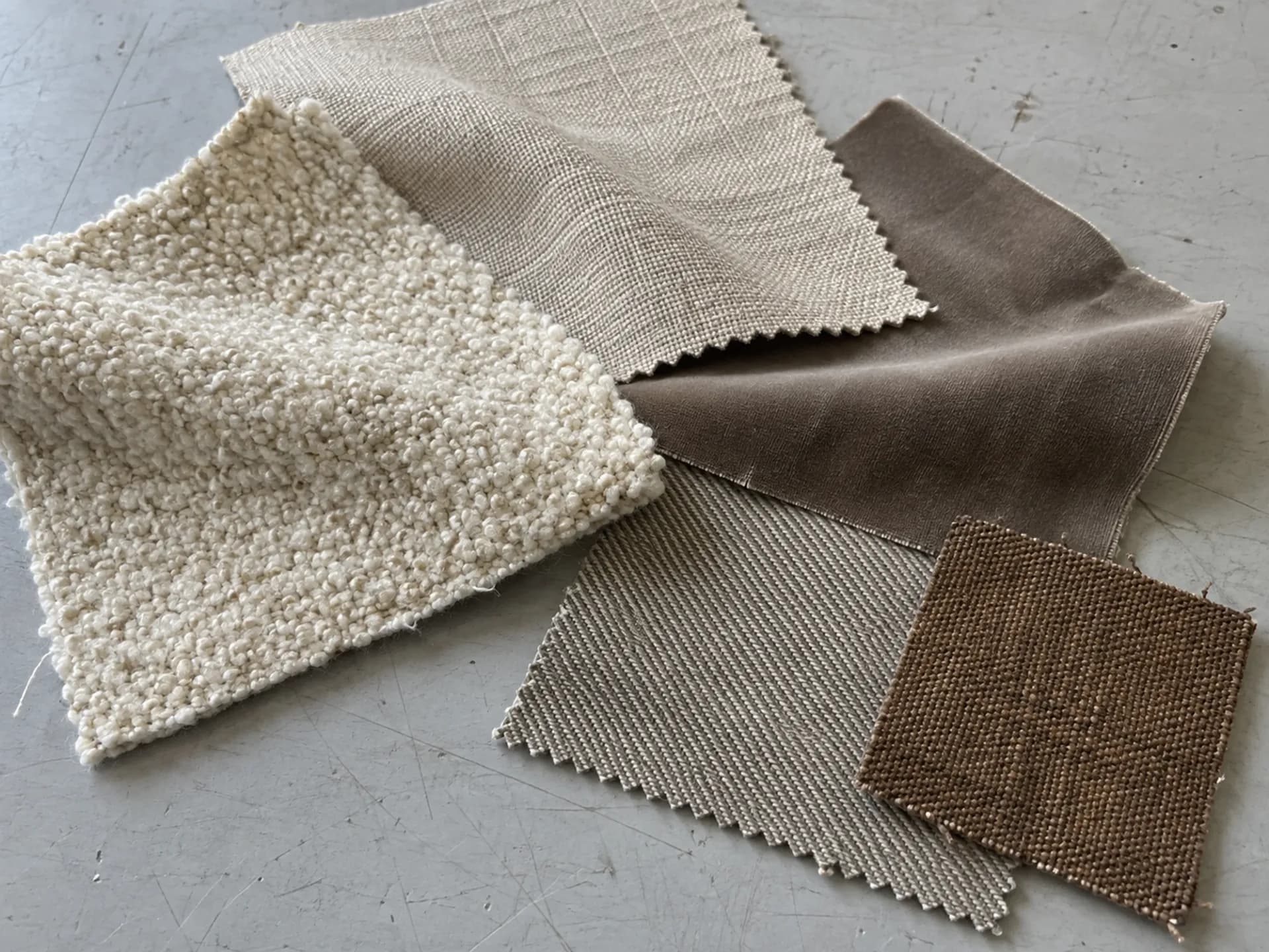 Overlapping neutral upholstery fabric swatches showing different weaves