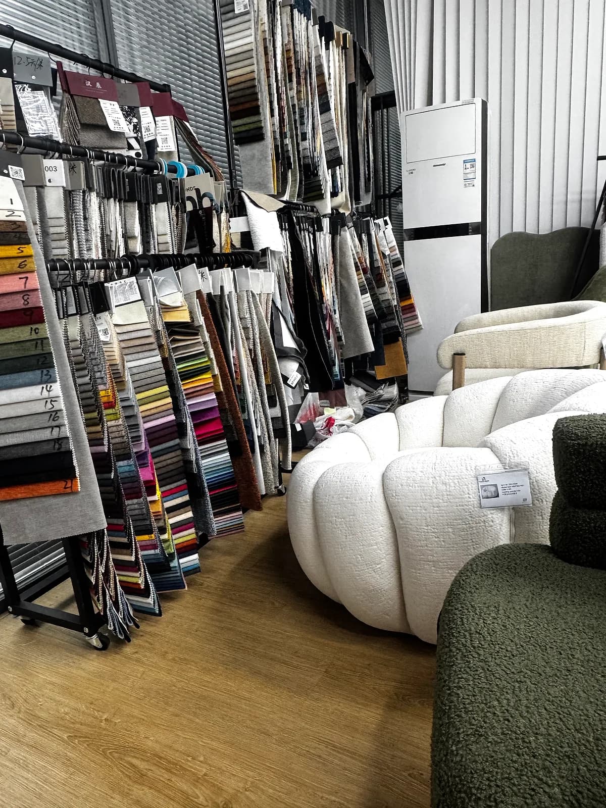Upholstery fabric swatch library beside a white pumpkin chair at the CasaViva studio